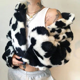 Person wearing a black and white polka dot fur coat with tattoos visible on arms.